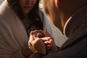 Boyfriend warming hands of his girlfriend by breath at walk in city