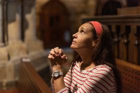 Hispanic woman praying with clasped hands in cathedral