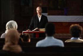 Preacher reading prayer for people in church