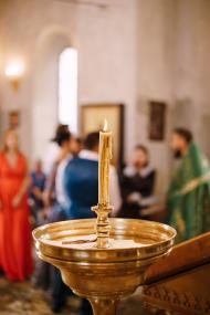 Wax candle burns on a stand in a large bowl in a temple