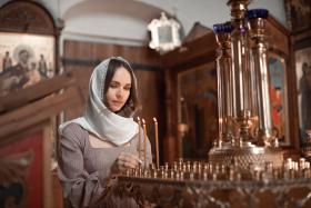 Young beautiful woman in the Orthodox Church lit candles in a ca