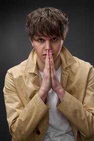 young man in coat holding hands in pray