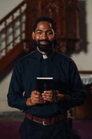 Young priest smiling and holding bible in church
